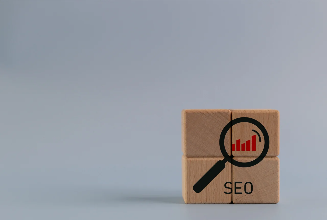 Cubos de madeira com ícone de lupa e SEO, simbolizando como os motores de pesquisa decidem o ranking e a autoridade de um site.